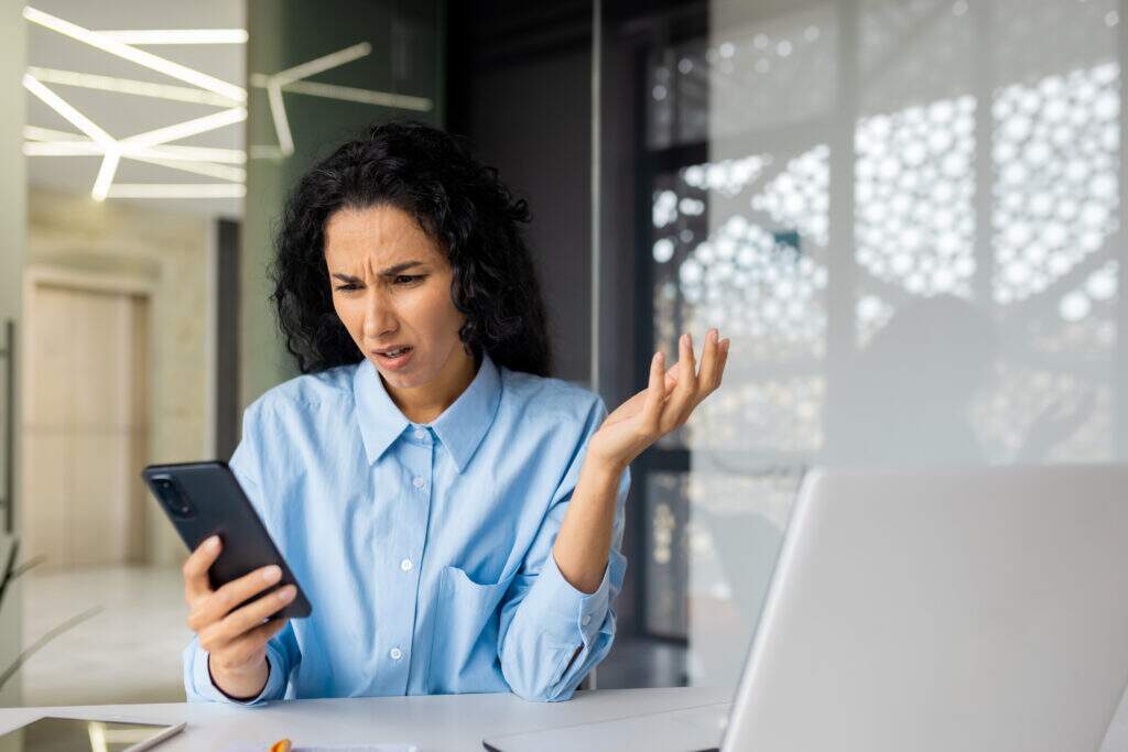 mulher expressando rosto de indignação lendo no celular 